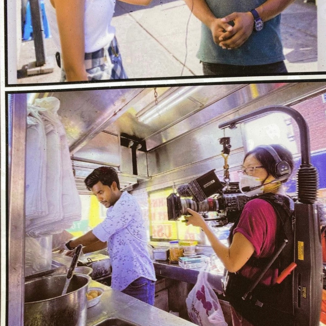 Jia Lia, an Asian woman with pulled-back hair and mask, films a man of color with her Stedicam as he works in a food truck.