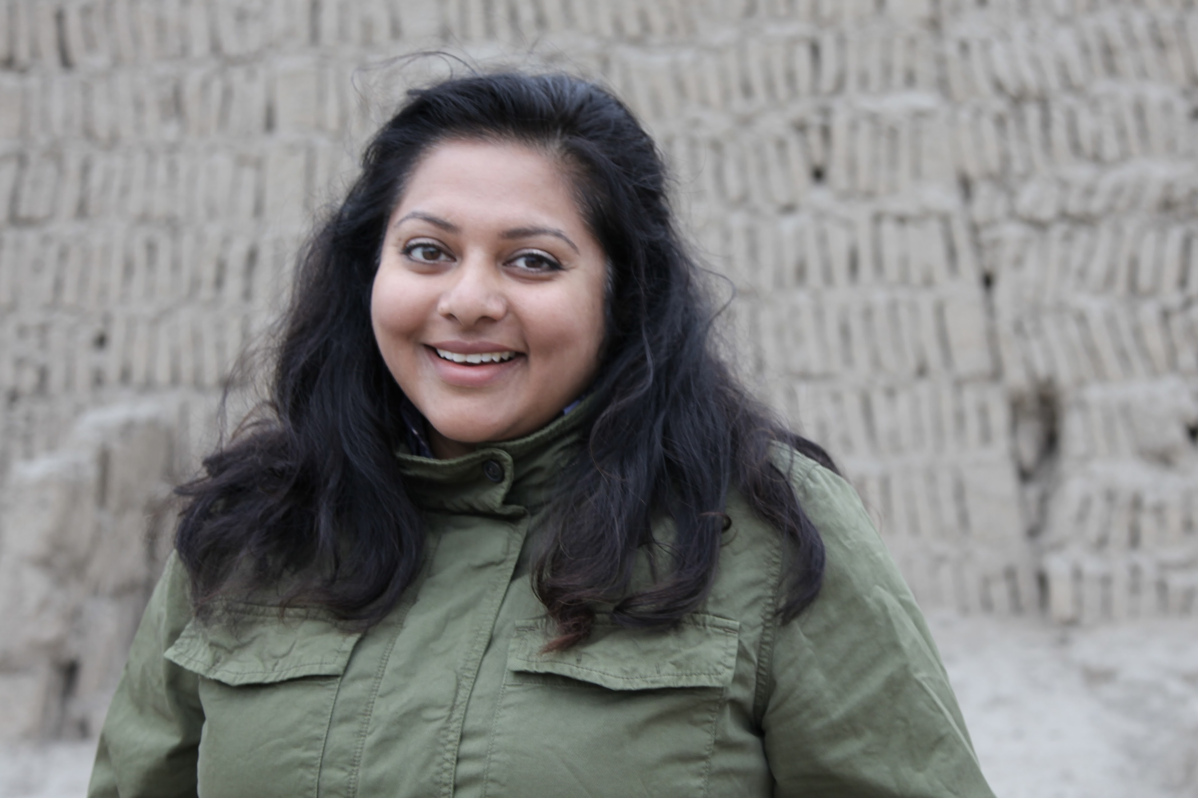 Nivedita Das is an Indian woman with long black hair pass her shoulderes. She is wearing an olive jacket.