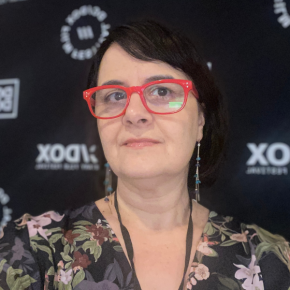 Marga Verea is a hispanic woman with side-swept brown bangs and bright red glasses.