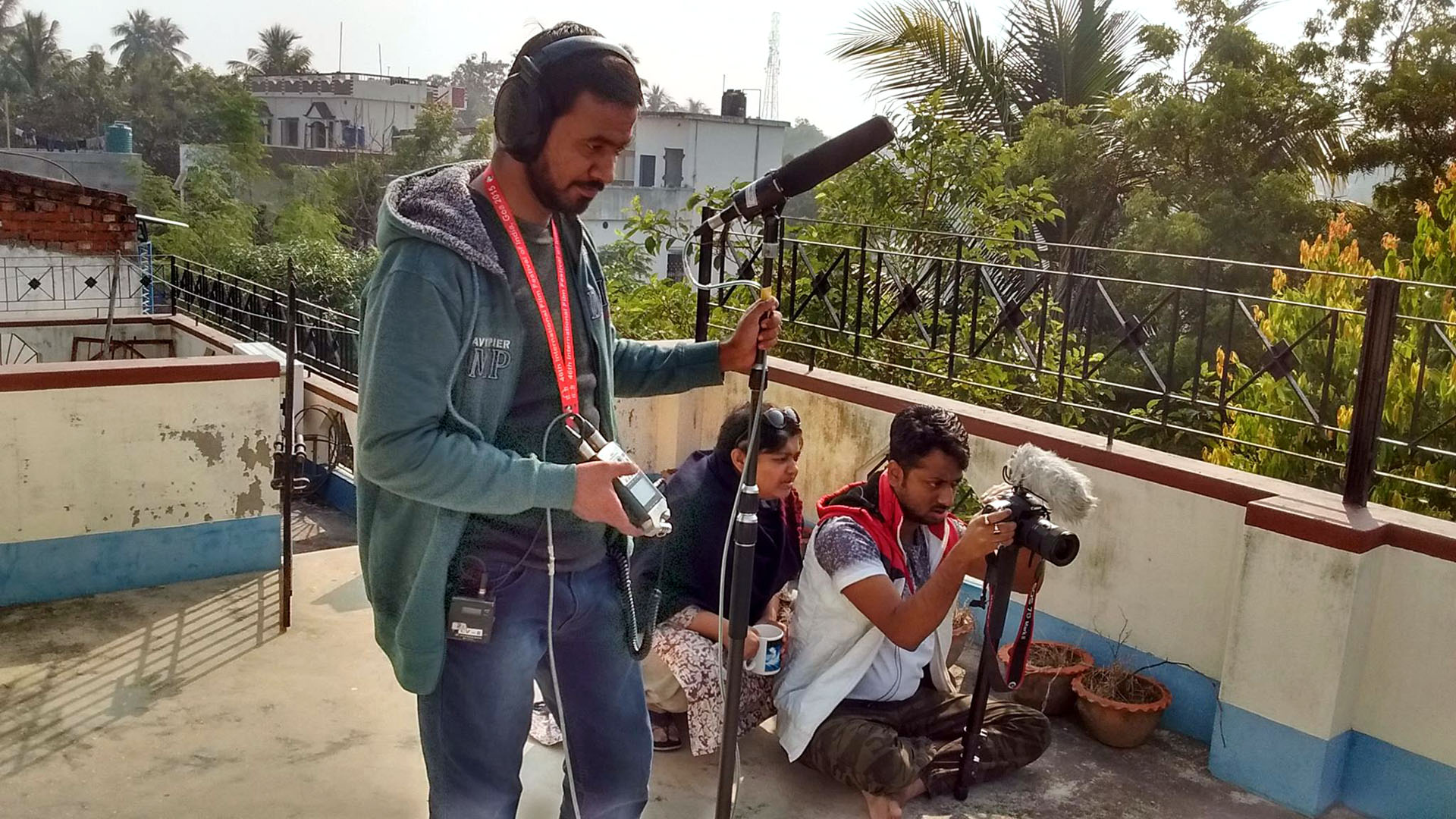 On a rooftop in India, Moupia, a camera man and a boom operator film.