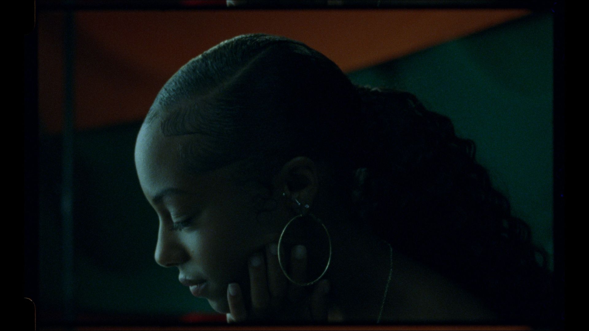 Profile of a Black woman looking down in a dark room