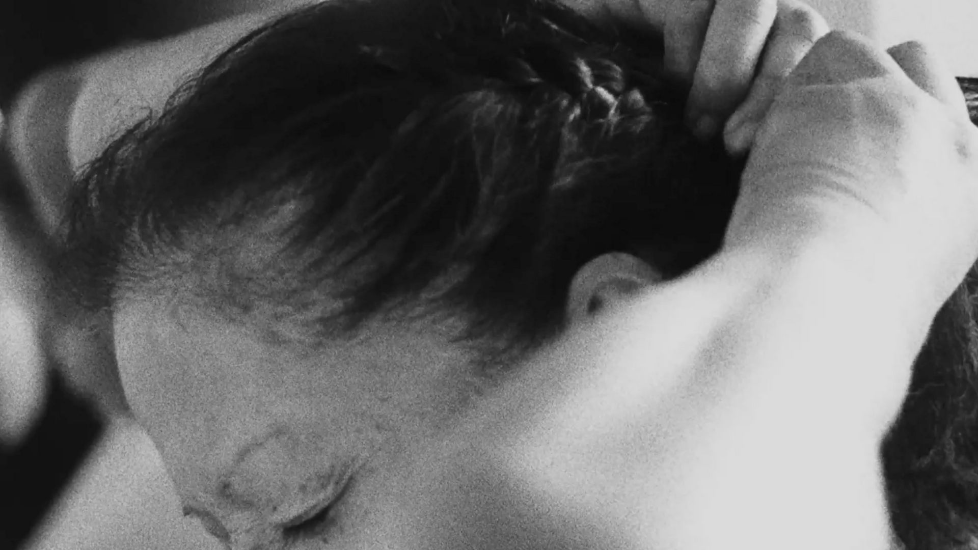 In black and white, Latina woman ties back her hair.